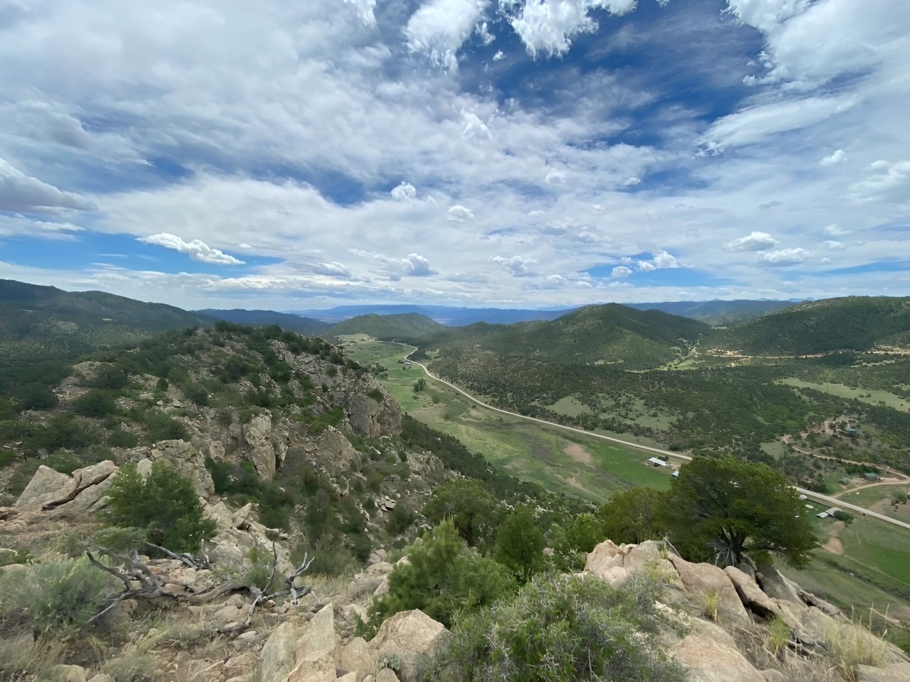 Scenic Vista From a Mountain Peak, Revealing Towering Mountains and a Sprawling Valley Below, Highlighting the Landscape’s Grandeur.